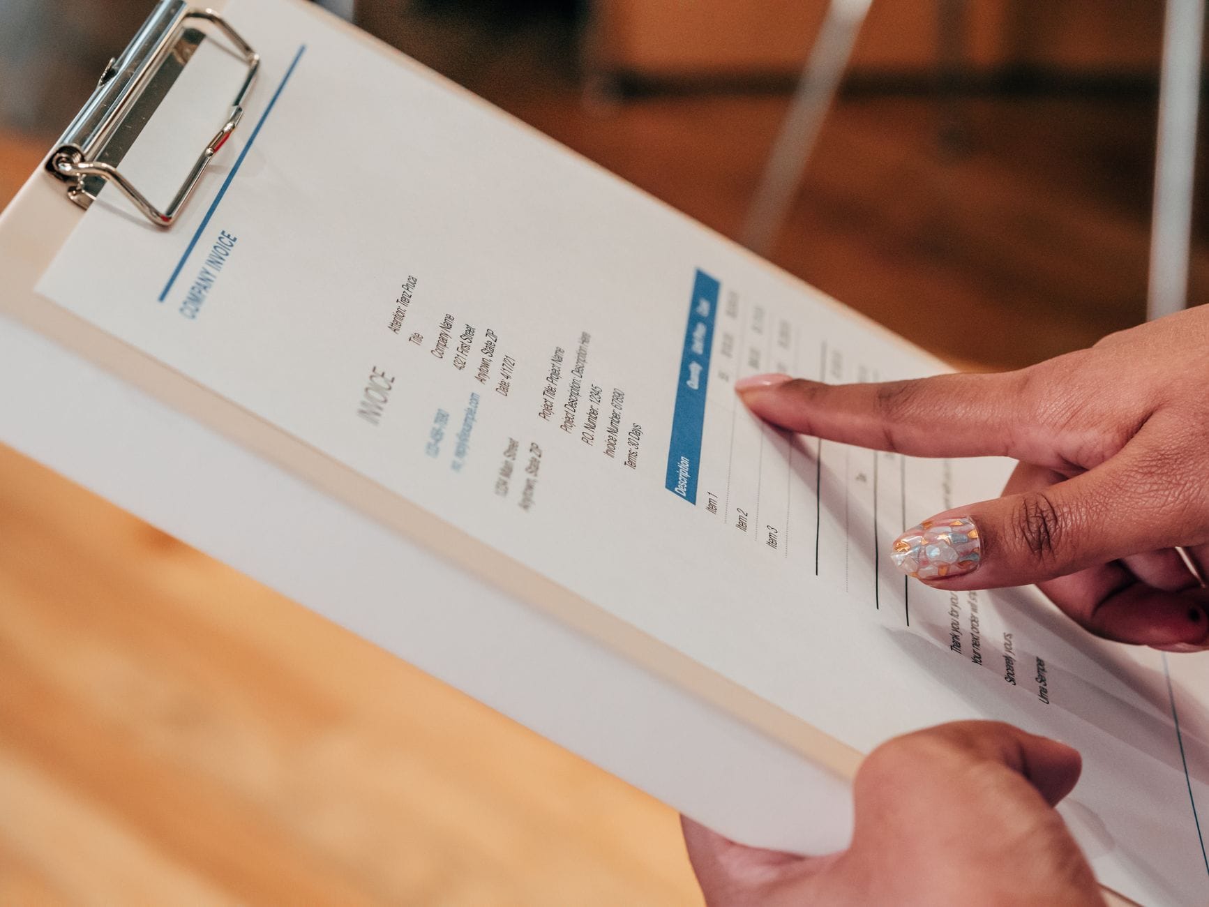 Des mains qui trient des papiers et des factures sur un coin de bureau.