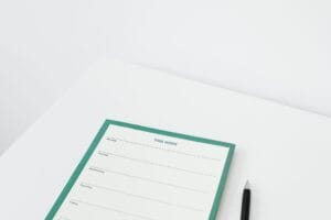 Un agenda papier ouvert sur un bureau clair, avec un téléphone et un stylo posés à côté.
