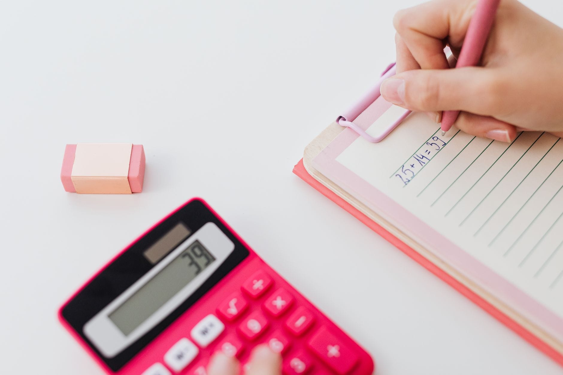 Des mains posées sur une calculatrice, à côté d'un agenda ouvert et d'un stylo.