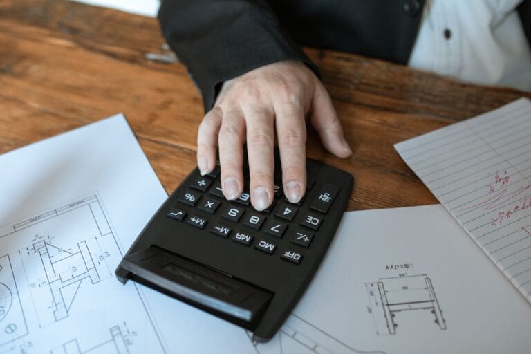 Un bureau clair avec des factures empilées, une calculatrice et un carnet ouvert.